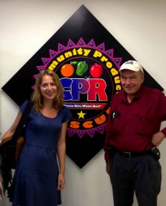 Daniella Uslan and David Hibler pose in front of the Community Produce Rescue sign in Omaha, Nebraska