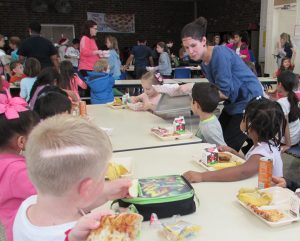 Adult serving healthy food to children in a school cafeteria