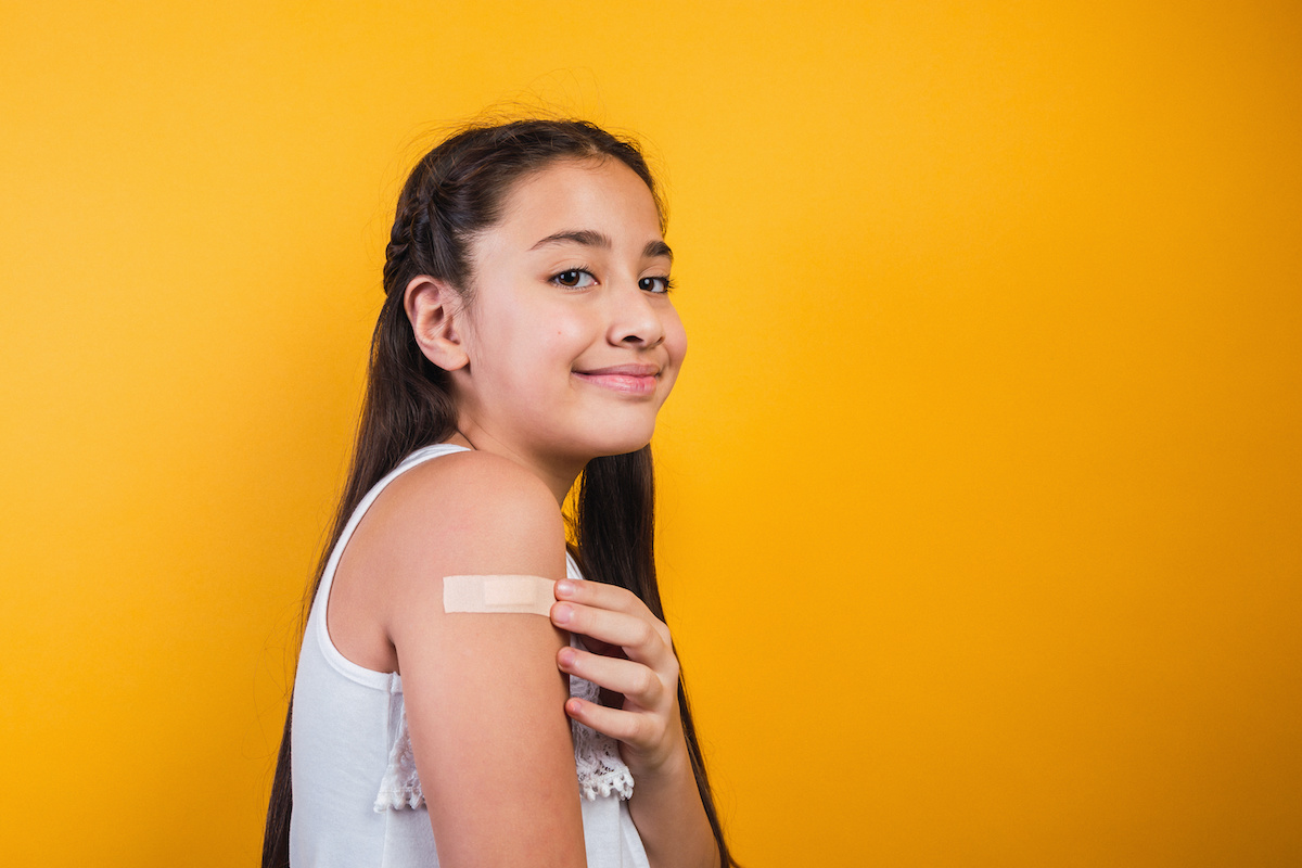 Adolescent girl smiling with band-aid on arm