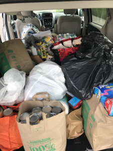 Trunk of a vehicle filled with bags and boxes of canned food and other hurricane relief items