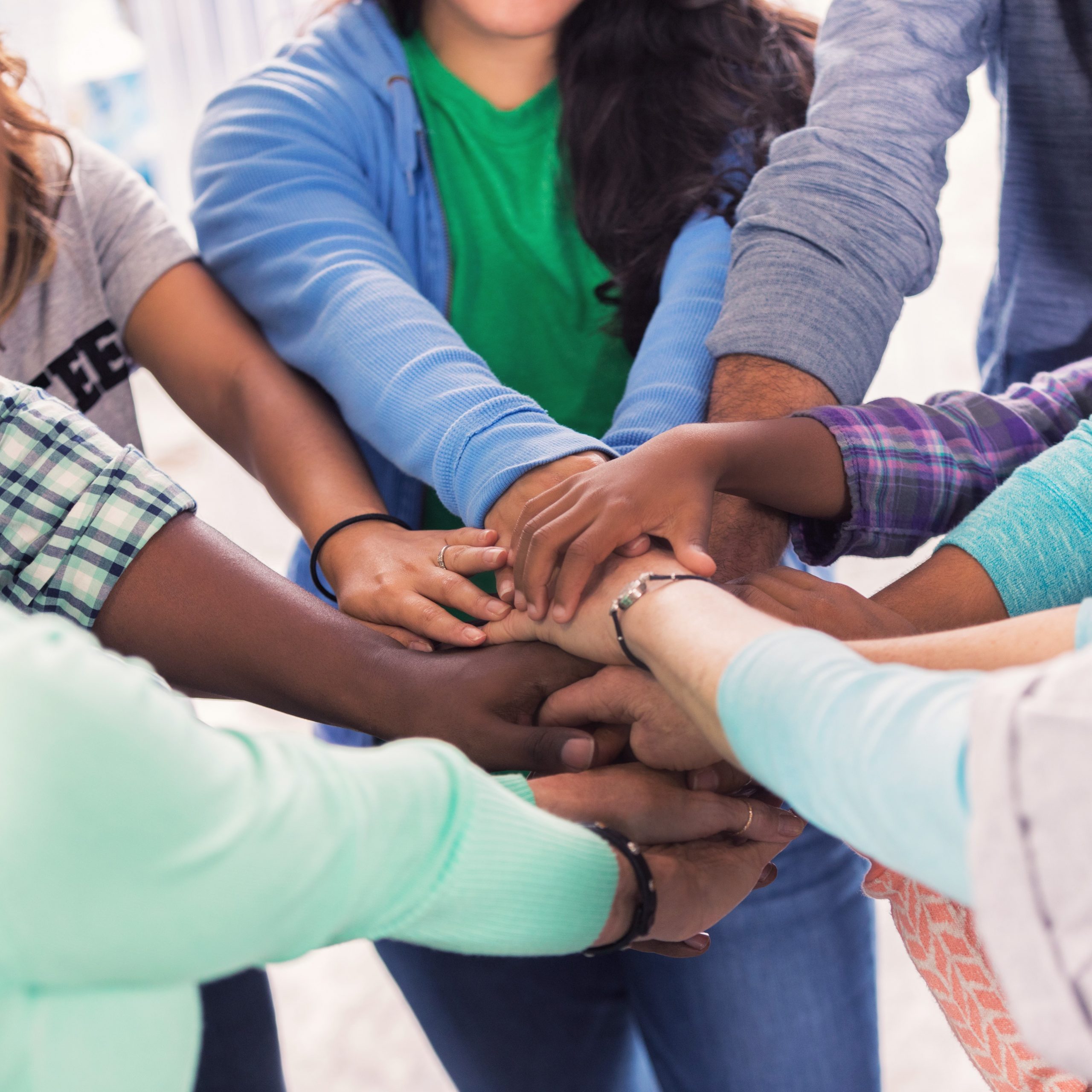 Diverse group of people with hands together in a circle