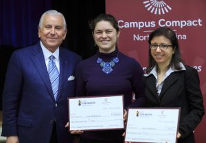 Photo of board member with two winners holding checks