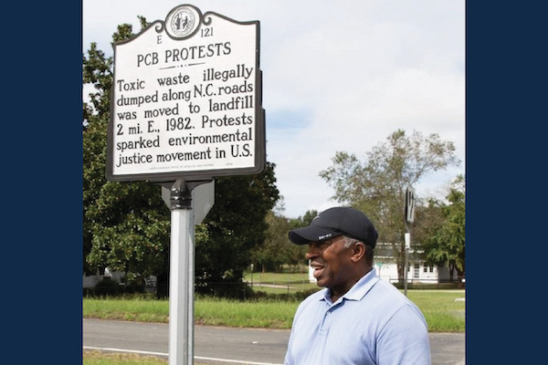 Rev Bill Kearney in front of Warrenton's sign commemorating the PCB Protests that birthed the environmental justice movement