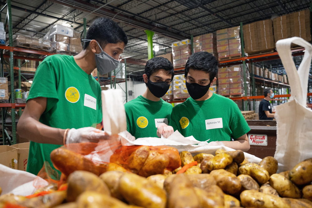 Siddharth Maruvada, Arnav Meduri, and Abhinav Meduri, the high school students who created Pantry Patrol, sort through potatoes at the Food Bank of Eastern and Central North Carolina in Raleigh. While volunteering, they’re also noting potential features that may be useful to add to their app. (photo by Elise Mahon from UNC Research)